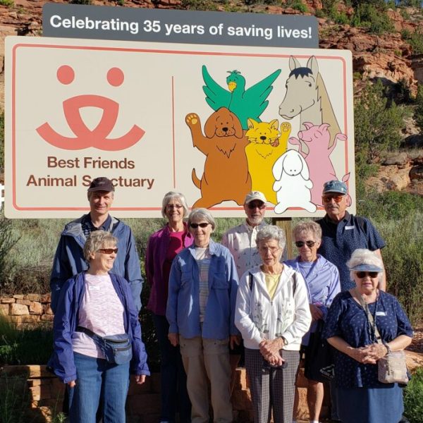 a group of people standing in front of a sign posing for the camera