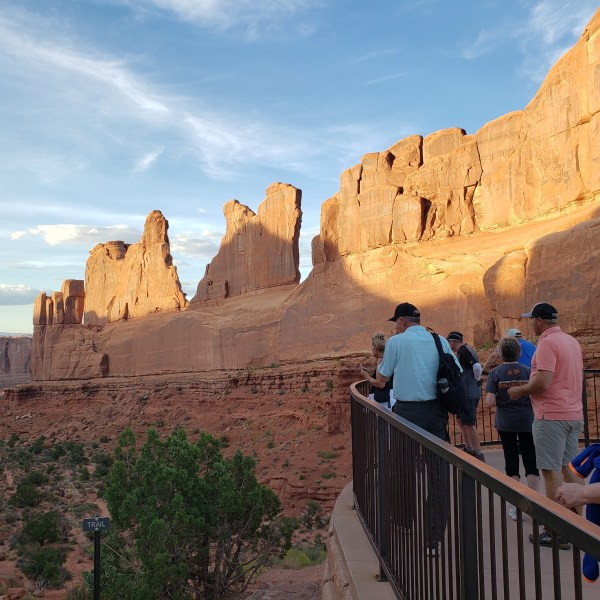 a group of people standing in front of a canyon with Arches National Park in the background