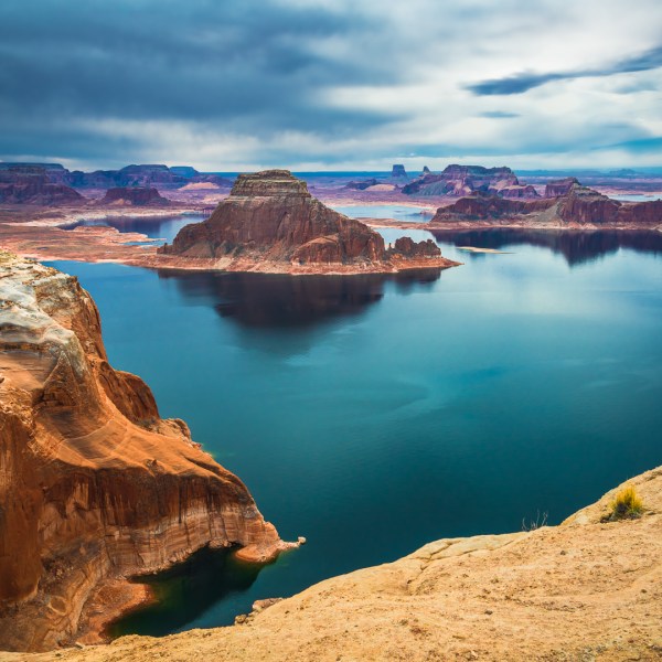 a rocky island in the middle of a body of water with Lake Powell in the background
